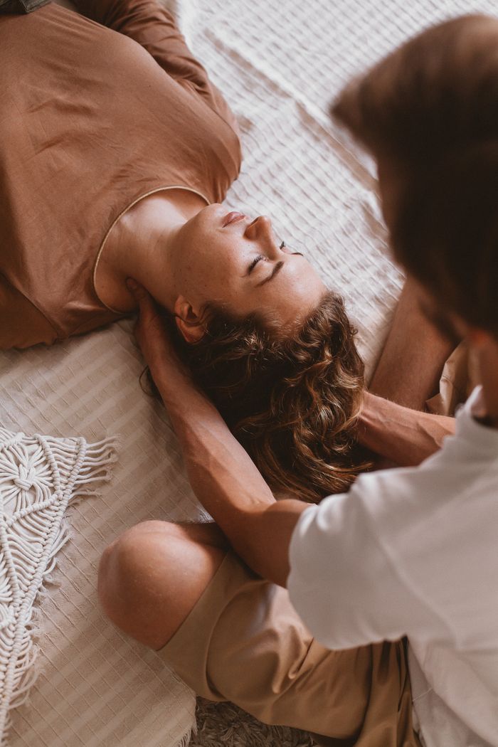 A man and woman lying together on a textured surface, eyes closed, enjoying a calm moment.
