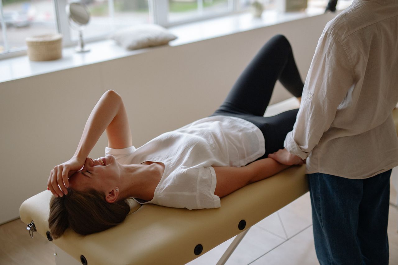 Woman in white top enjoying a relaxing massage session indoors, smiling and lying comfortably.